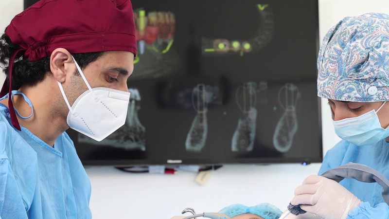 Two clinicians at Dental Studio working with the 3D implant plan on the screen behind them